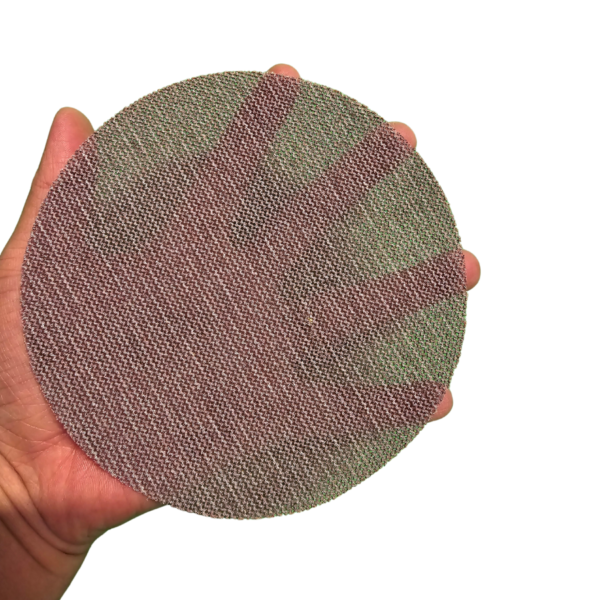 A person holding a mesh sanding disc against a white background