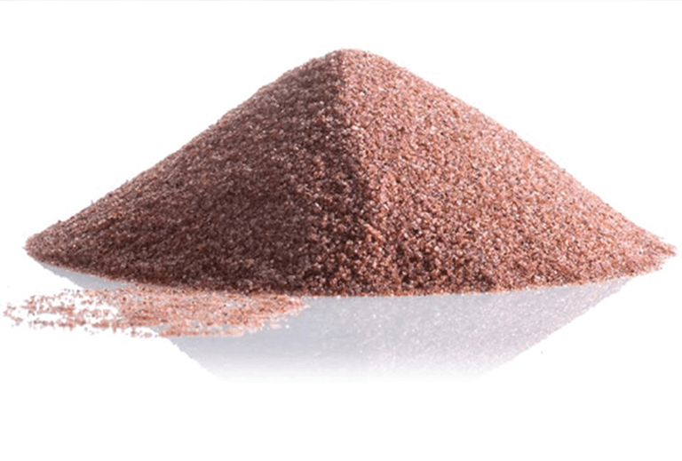 A pile of red garnet abrasive sand on a clean white background, showcasing its vibrant color and texture.